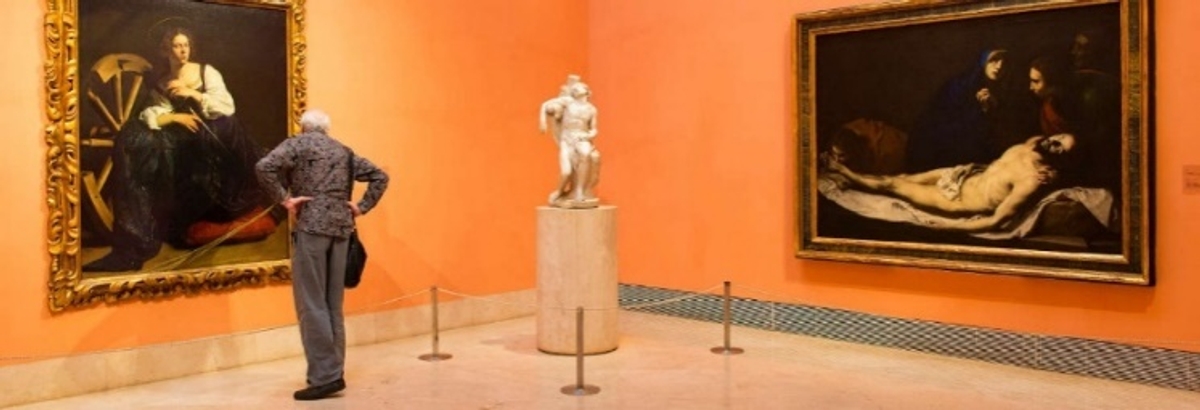 Un visitante observa obras de arte en una galería con paredes de color naranja.