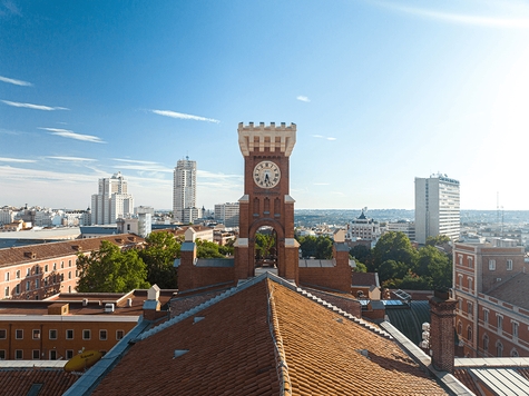 Vista de un paisaje urbano con un edificio histórico y un reloj en primer plano.