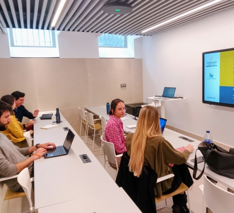 La imagen muestra a un grupo de personas participando en una reunión en una sala de conferencias.