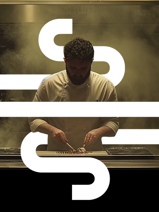 Un chef trabaja en una cocina moderna mientras el vapor llena el aire.