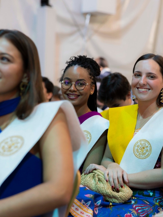 Un grupo de personas sonríen mientras asisten a una ceremonia de graduación.