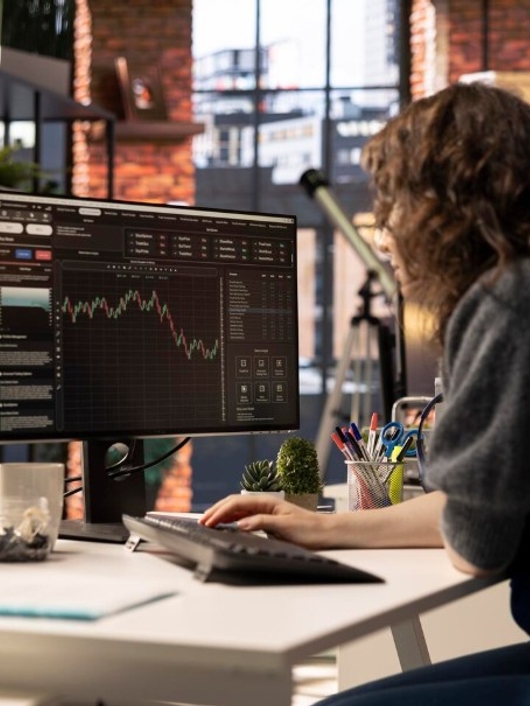 Una persona trabaja frente a varios monitores que muestran gráficos financieros en un entorno moderno.