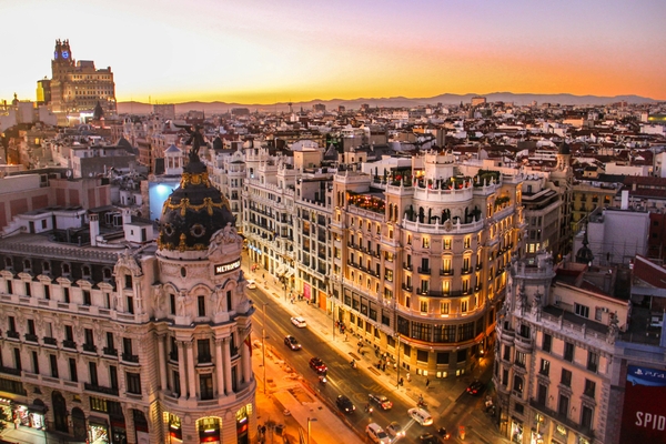 Una vista panorámica de la ciudad al atardecer, destacando edificios emblemáticos y calles iluminadas.