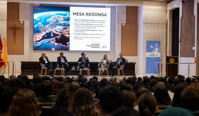 Una mesa redonda con varios ponentes discutiendo ante un gran público en un auditorio.