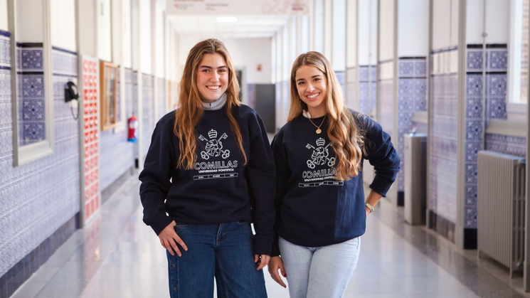 Dos mujeres jóvenes sonriendo en un pasillo de la escuela, ambas vistiendo sudaderas azules con el logotipo de 'Cobrillas'.