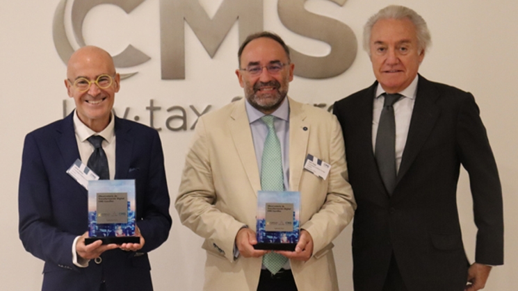 Tres hombres posan con premios en un evento formal.