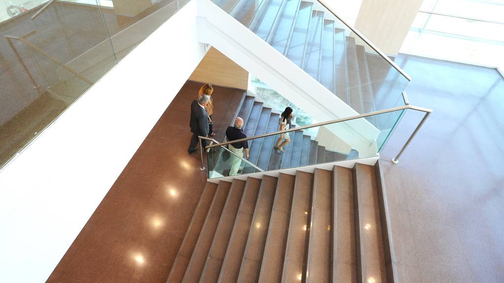 Una imagen que muestra un escalera moderna con tres personas en ella.