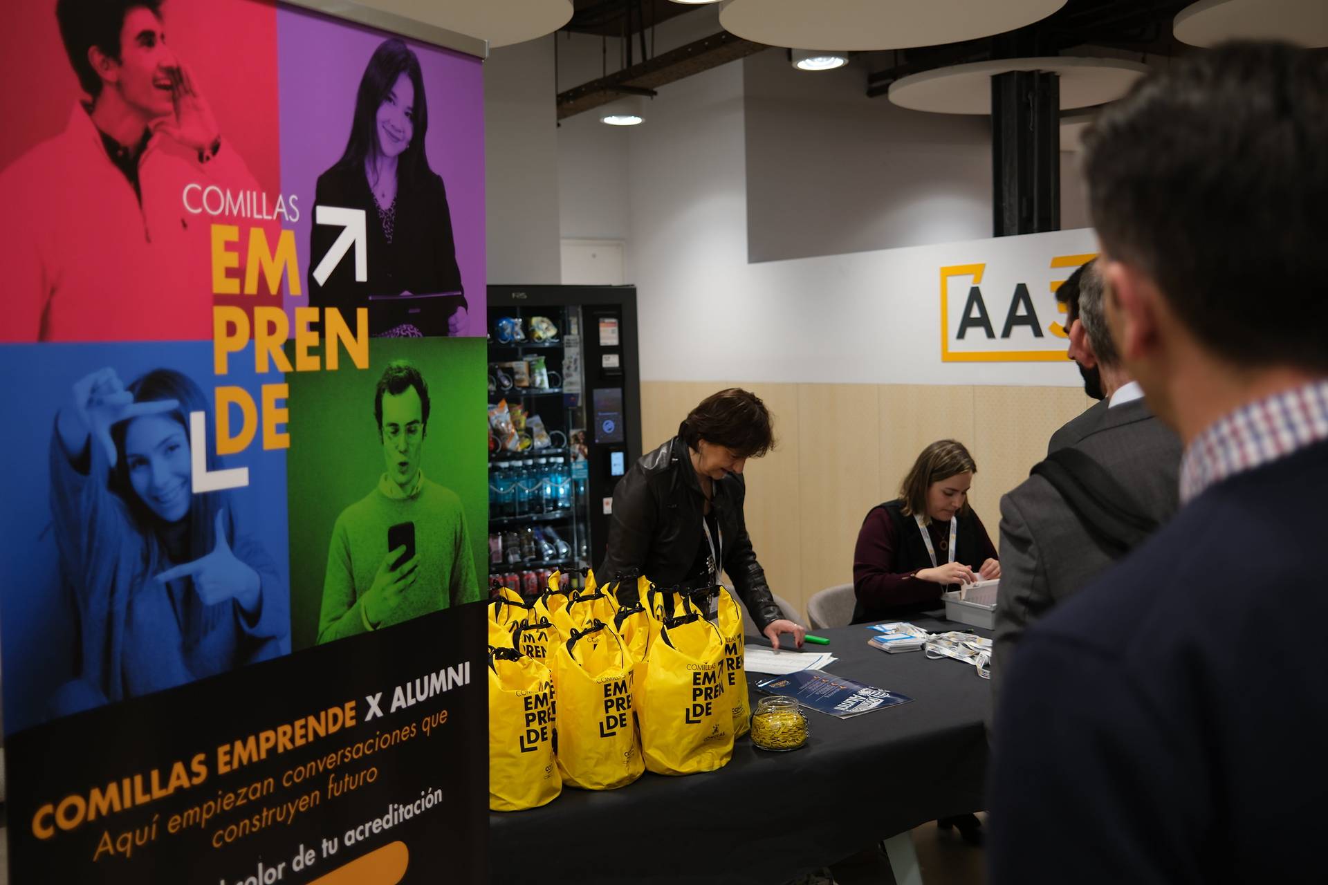 Una feria o evento donde se presentan actividades de emprendimiento con asistentes y un stand decorado.