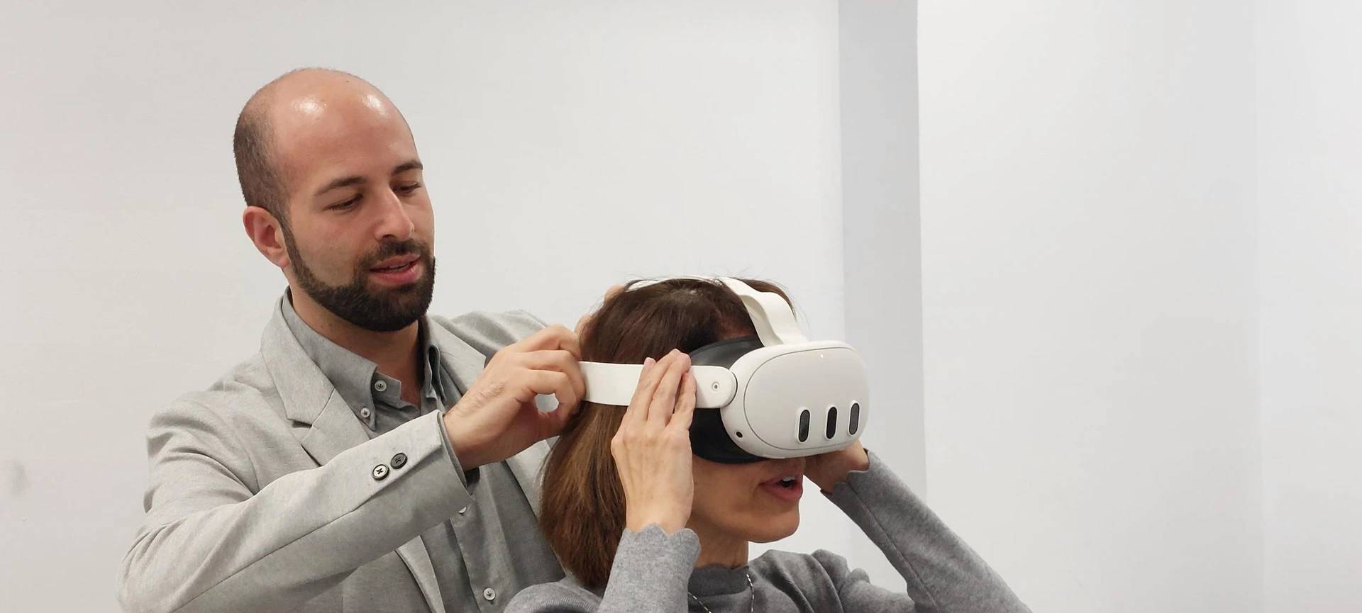 Un hombre ayuda a una mujer a colocarse un visor de realidad virtual.