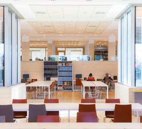 A modern and brightly lit library with tables, chairs and bookshelves.