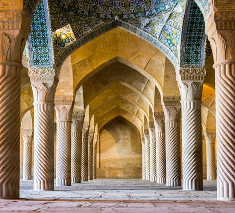 Un interior de columnas con arcos en un edificio monumental que destaca por su arquitectura islámica.