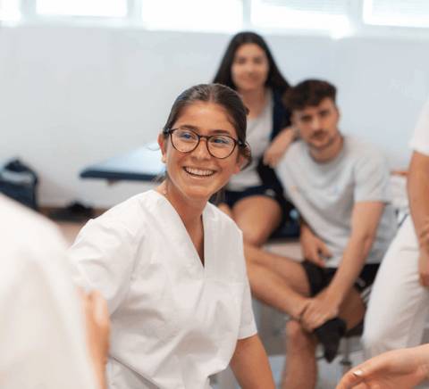 Un grupo de estudiantes en un ambiente académico, con una joven sonriendo en primer plano.