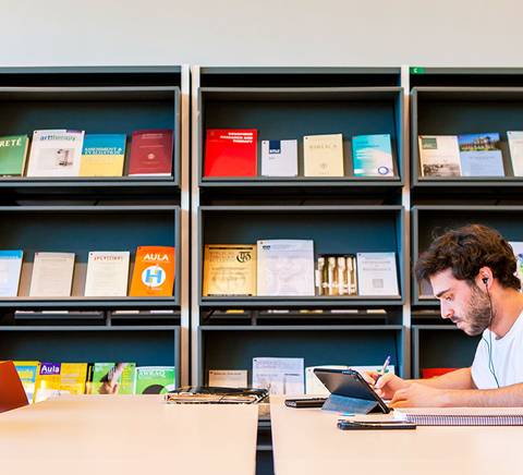 chico estudiando en biblioteca con tablet