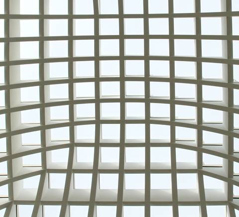 El interior de una estructura arquitectónica con un techo de rejilla que permite el paso de luz.