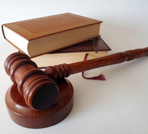 Un mazo de juez y libros de leyes están dispuestos sobre una superficie blanca.