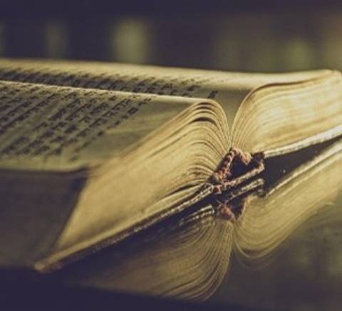 Un libro antiguo con páginas amarillentas reposando sobre una superficie brillante.