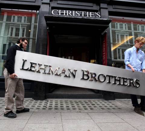 Dos hombres están llevando un letrero de metal que dice 'Lehman Brothers' frente a la casa de subastas Christie's.