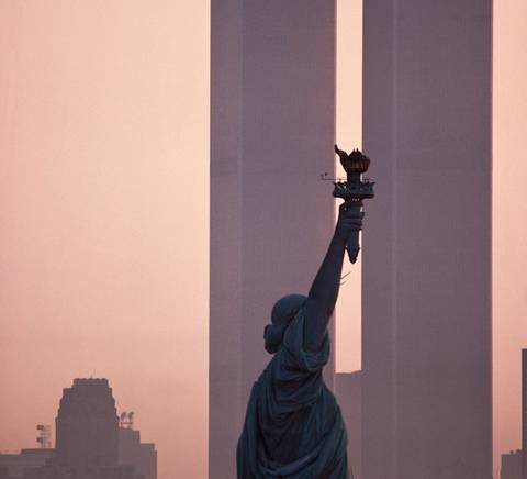 La imagen muestra la Estatua de la Libertad frente a las Torres Gemelas durante el amanecer.