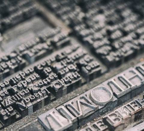 La imagen muestra una serie de caracteres de imprenta dispuestos en una superficie metálica.