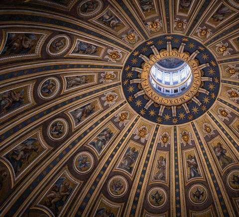 La imagen muestra el impresionante techo circular de una cúpula con ornamentos dorados y frescos.
