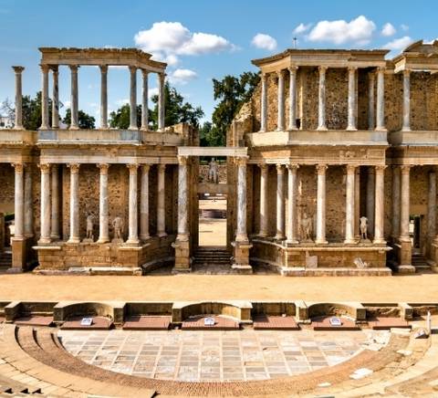 Ruinas de un antiguo teatro romano con columnas y un escenario visible.