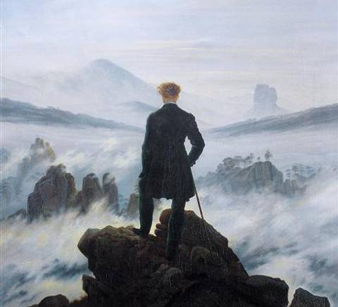 Un hombre de espaldas contempla un paisaje montañoso envuelto en neblina.