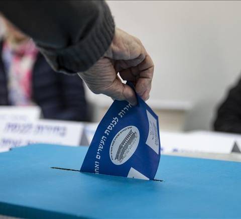 Una persona está votando al introducir una boleta en una urna electoral.