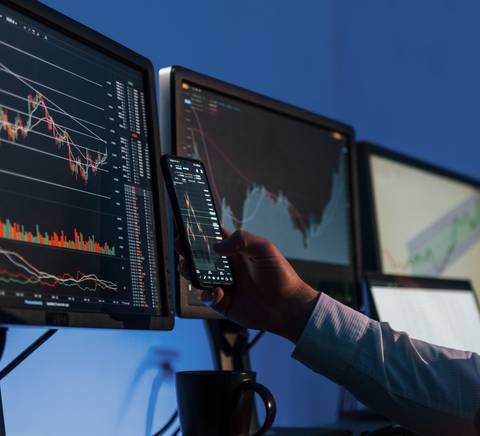 A person analyzing financial markets on multiple computer screens.