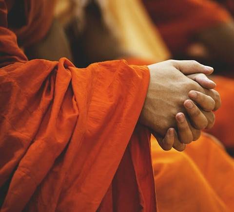 Las manos de un monje en un entorno de meditación.