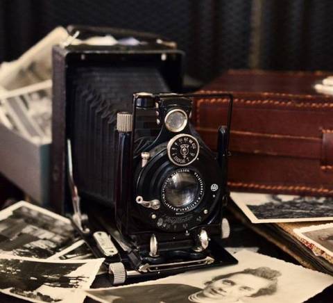 Una antigua cámara de fotos rodeada de fotografías en blanco y negro.