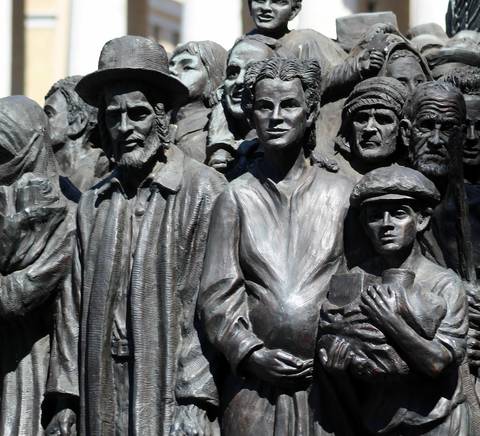 La imagen muestra un grupo de esculturas de personas en diferentes actitudes y vestimentas, representando una multitud en un contexto emocional.