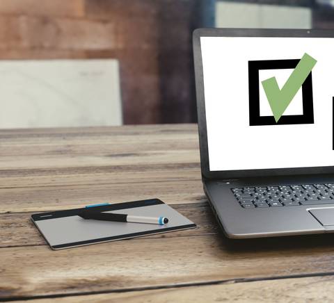 Un ordenador portátil muestra un ícono de verificación y un cursor sobre la pantalla.