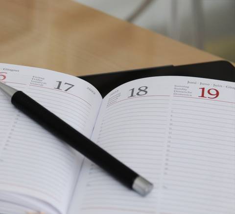 Una agenda abierta con un bolígrafo negro sobre ella, mostrando las fechas del 16 al 19.