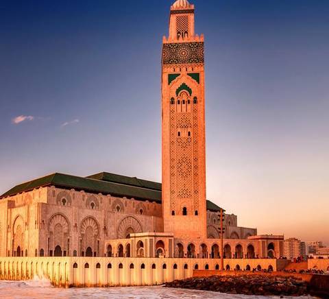 Una majestuosa mezquita se alza junto a la costa durante el atardecer.