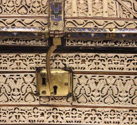La imagen muestra un detalle de un objeto artístico tallado con intrincados diseños geométricos y florales.