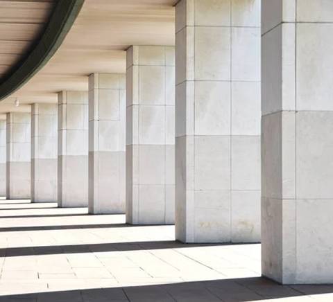 Una serie de columnas de concreto alineadas bajo una estructura arqueada.