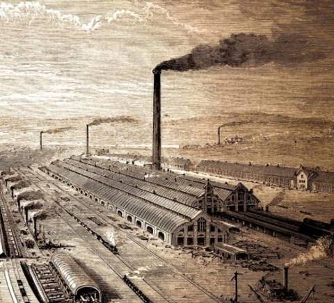 Una vista panorámica de una zona industrial con chimeneas humeantes y vías de tren.