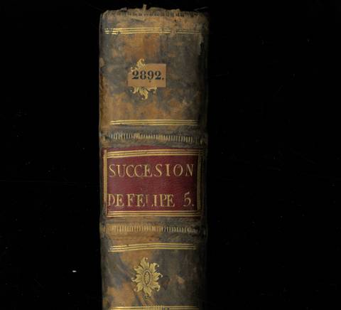 Un libro antiguo encuadernado en cuero con el título 'Sucesión de Felipe 5' en la portada.