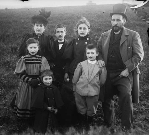 Fotografía en blanco y negro de una familia de siete miembros posando en un campo al aire libre.