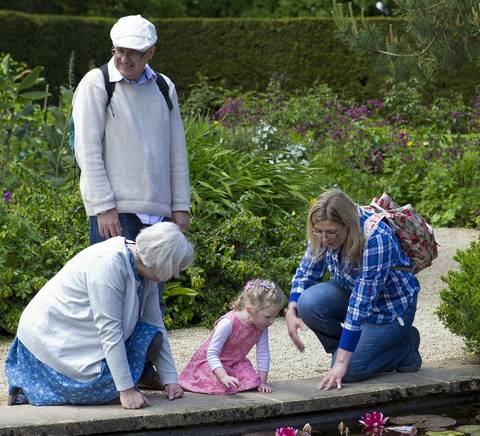 Una familia disfruta de un día en el jardín, observando los lirios en un estanque.