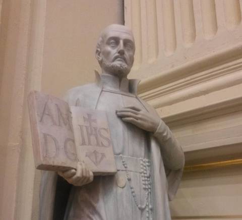 Estatua de un santo sosteniendo un libro y un rosario.