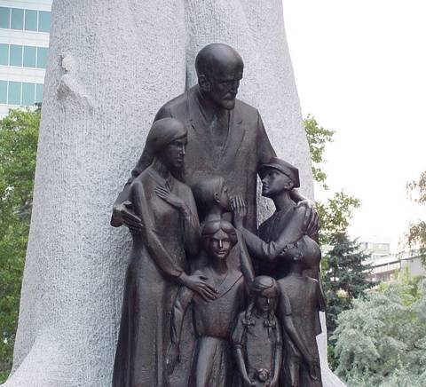 Una escultura que representa a un grupo familiar junto a un hombre mayor.