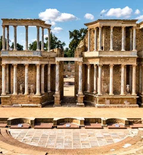 Ruinas de un antiguo teatro romano con columnas y un escenario visible.
