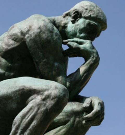 Una escultura de un hombre pensativo en una pose reflexiva.
