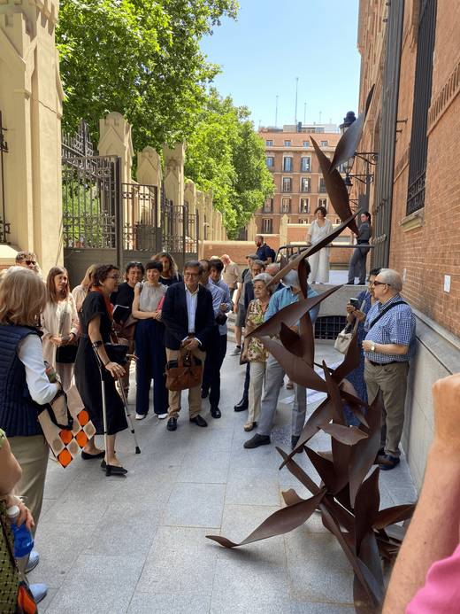 Un grupo de personas observan una escultura en un entorno urbano.