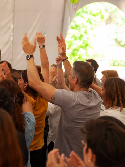 A group of people celebrating enthusiastically in a tent with their hands raised.