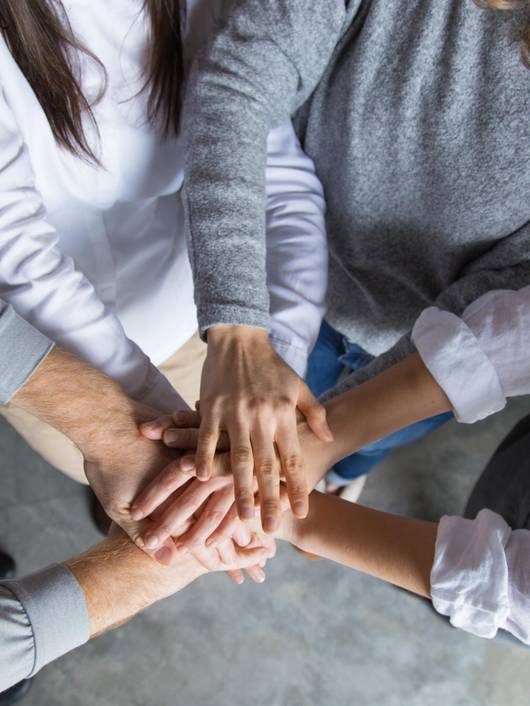 Un grupo de personas uniendo sus manos en un gesto de colaboración y unidad.
