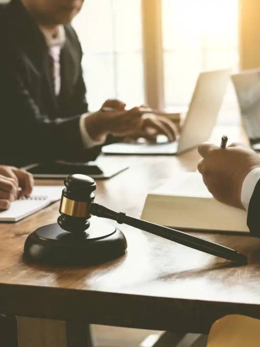 Una reunión de abogados en una mesa de trabajo con un martillo de juez en primer plano.