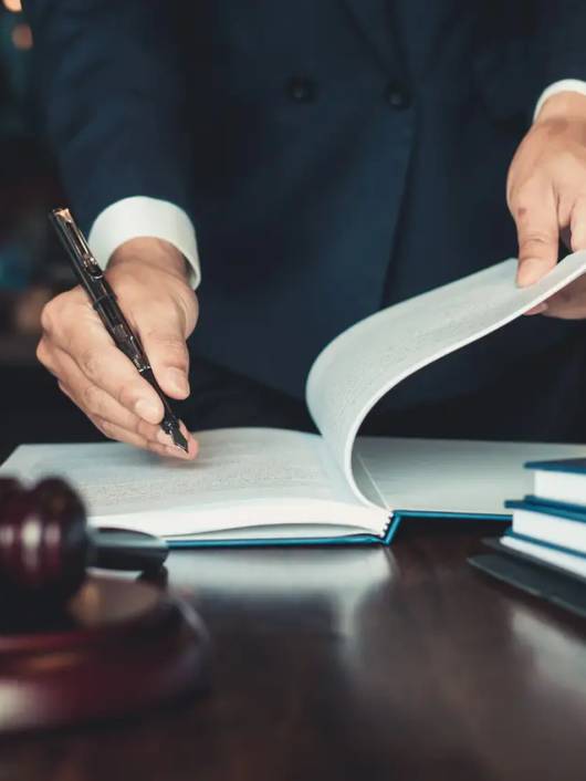 Un abogado está escribiendo en un libro mientras sostiene una balanza de la justicia a un lado.
