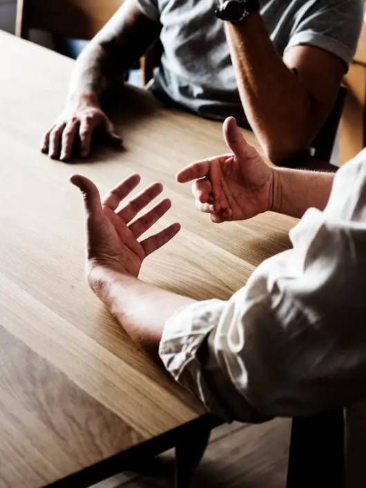 Un grupo de personas discutiendo en torno a una mesa de madera.